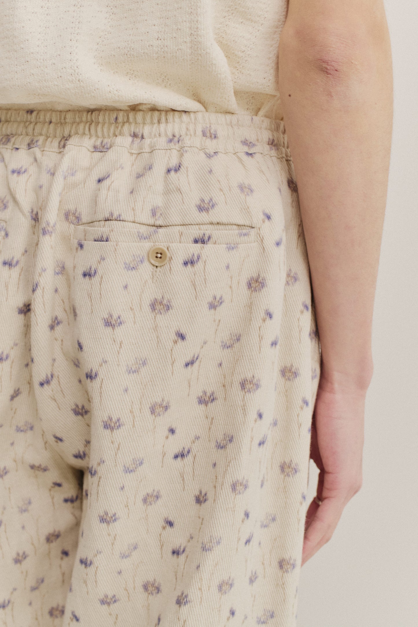 Men's long-pants, cotton-linen blend twill, ecru with subtle lilac floral print, elastic waist, welt pocket.