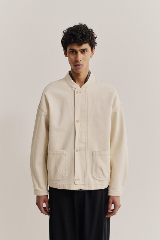 Men's outerwear jacket, organic cotton raw denim, off-white, boxy fit, stand-up collar, patch pockets.