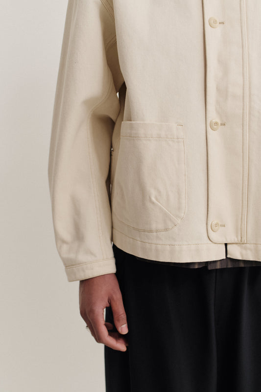 Men's outerwear jacket, off-white raw organic cotton, boxy fit, patch pocket, buttoned cuffs.
