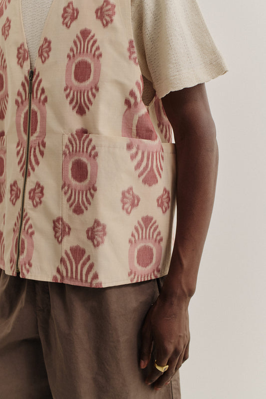 Men's outerwear vest, cotton-recycled polyester blend, ikat-patterned, beige with red print, metal zipper, and patch pockets.