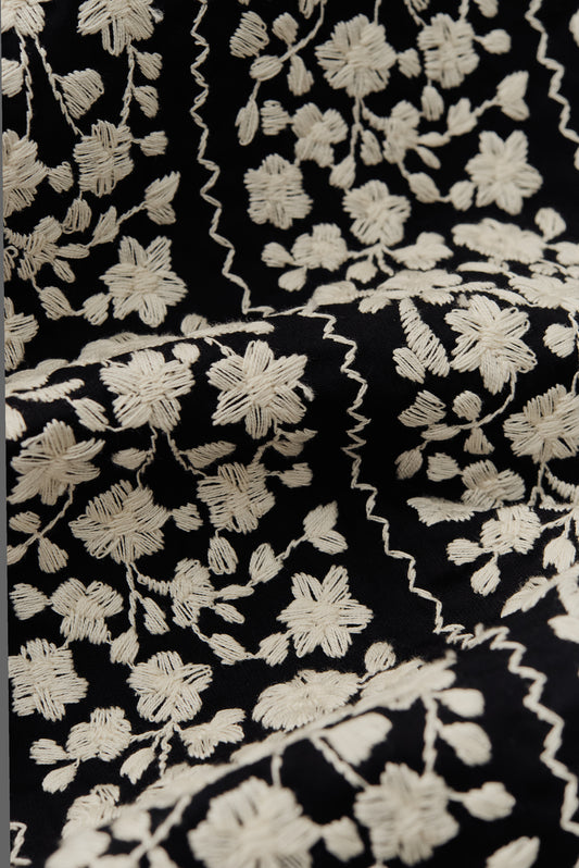 Women's outerwear vest, black cotton with white embroidered floral blocks and wavy lines.