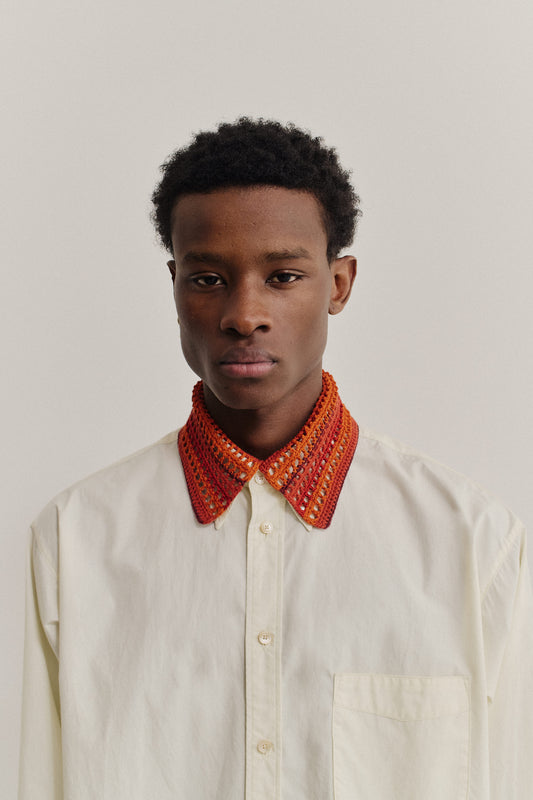 Men's accessories, hand-crocheted Kikoy Collar in orange and red merino wool, worn over a light cream cotton shirt.