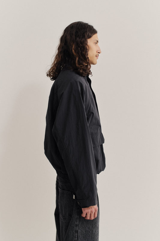 Men's outerwear jacket, recycled nylon and cotton blend, water-repellent, black, wide silhouette, deep raglan sleeves, bellows pockets.