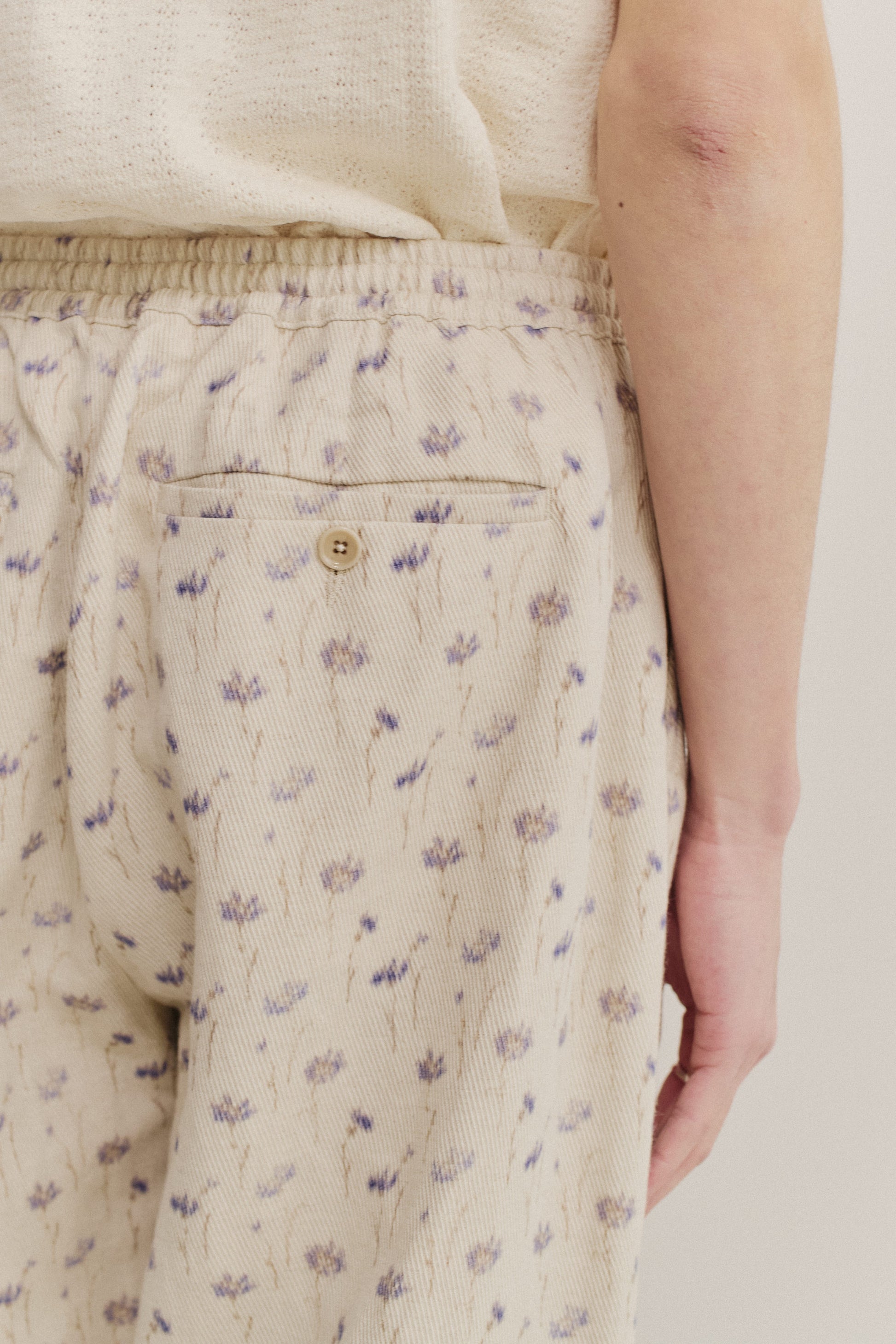 Men's long-pants, cotton-linen blend twill, ecru with subtle lilac floral print, elastic waist, welt pocket.