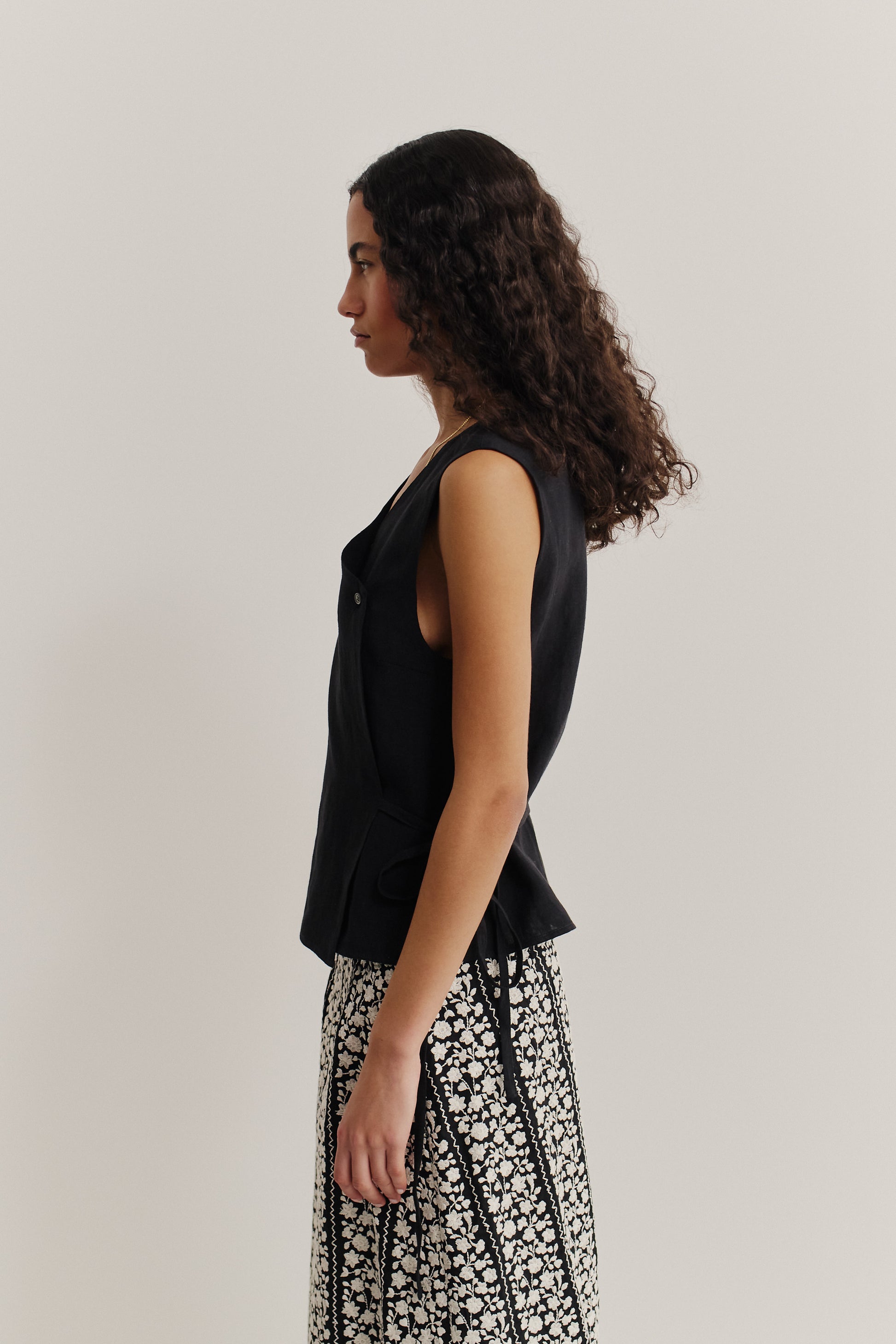 Women's sleeveless linen wrap shirt in natural black, featuring an asymmetric V-neck and side tie.