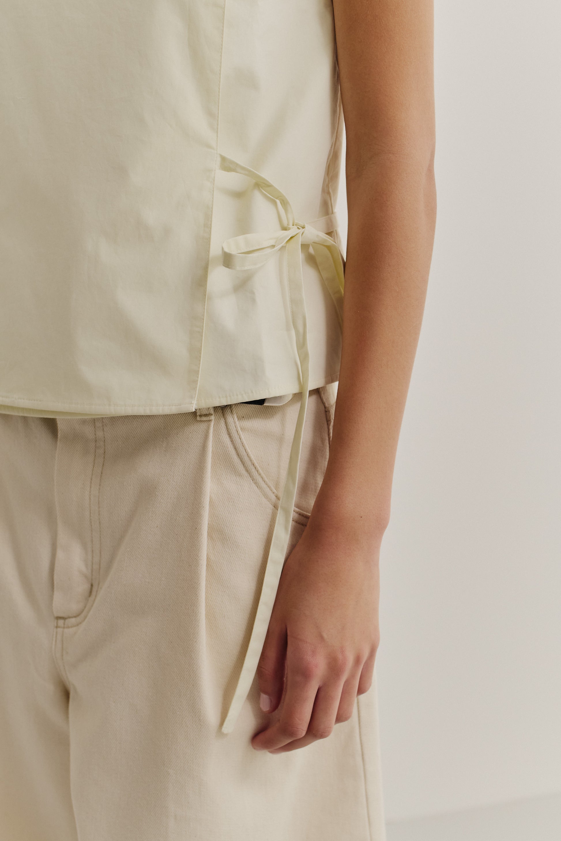 Women's sleeveless wrap shirt, organic cotton, garment washed, light yellow, with side ties.