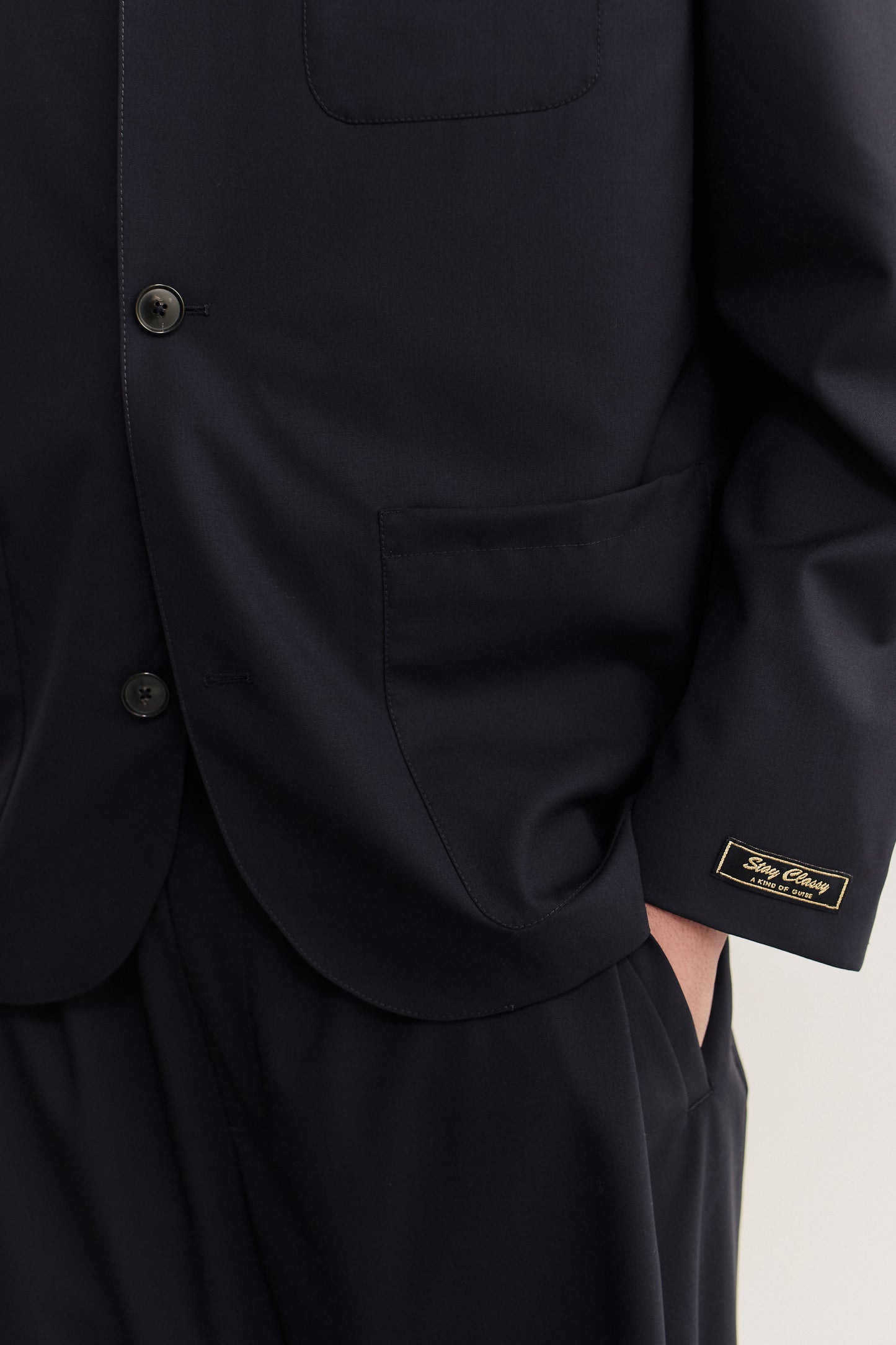 Men's tailoring blazer, 100% virgin wool, dark navy, with three patch pockets and "stay classy" label.