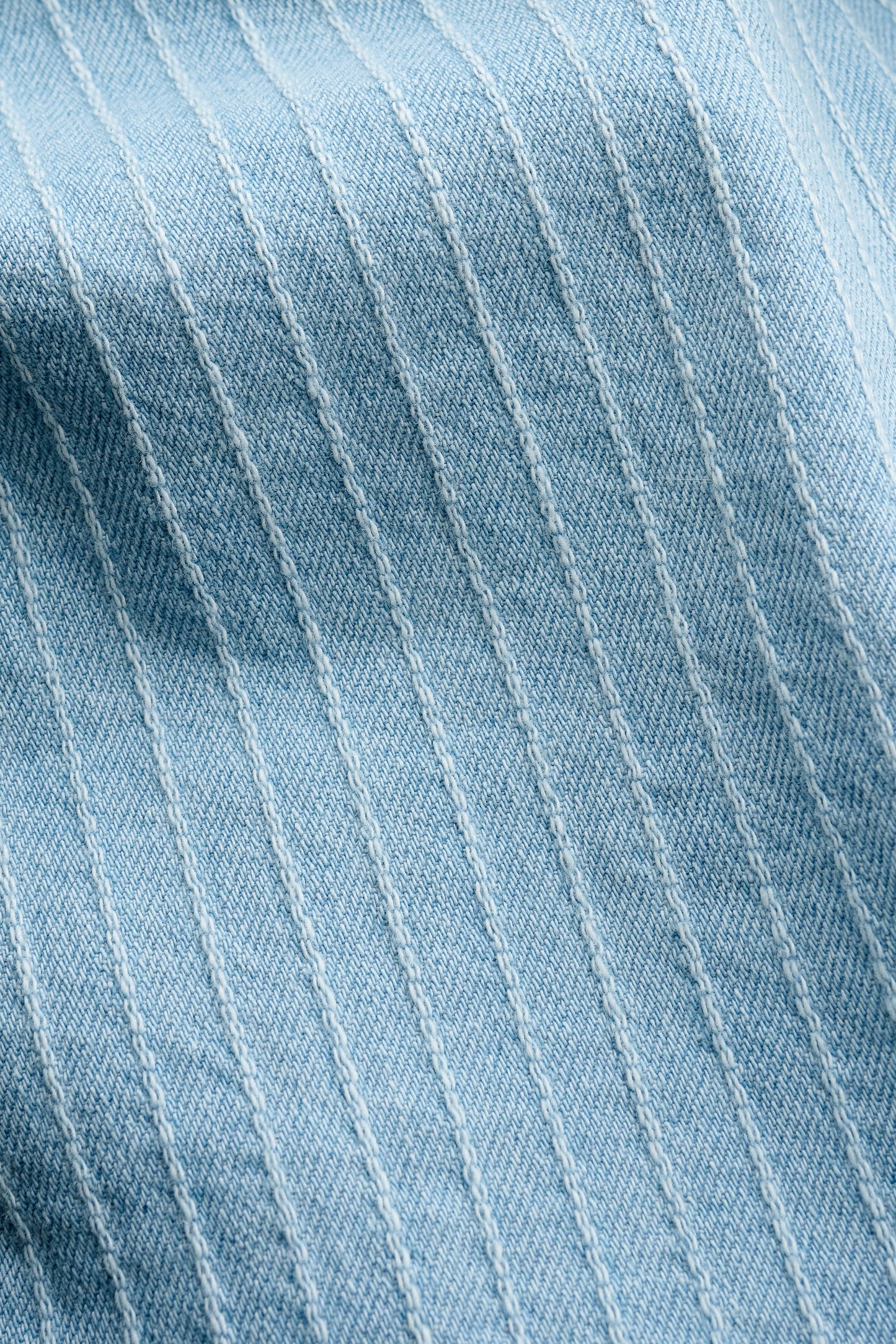 Men's long-sleeved shirt, light blue organic cotton denim with subtle white pinstripes and washed finish.