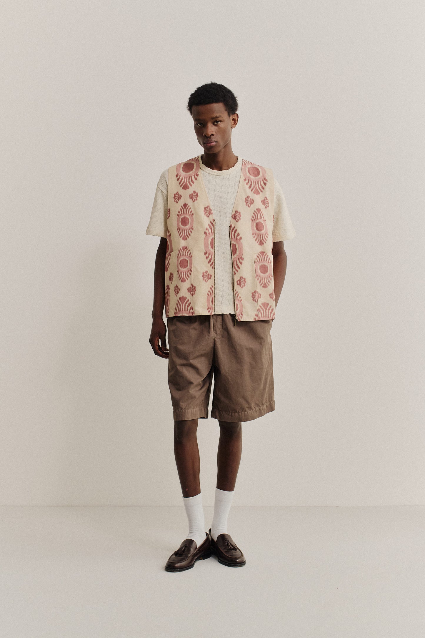 Men's outerwear vest, cotton-recycled polyester blend, ikat-patterned light pink and cream, metal zipper.