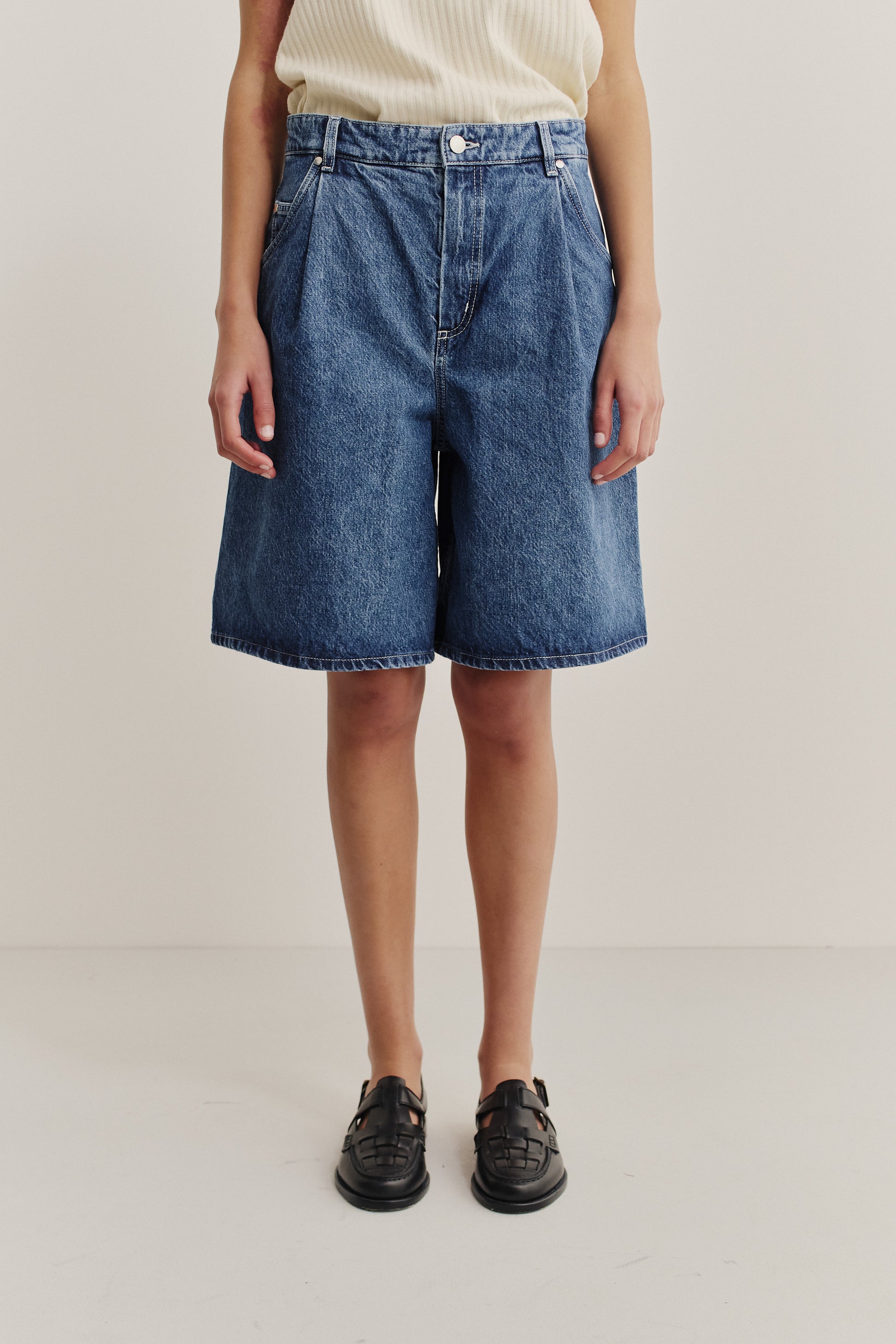 Women's shorts, wide-fit pleated denim, stone-washed indigo blue, made from organic and recycled cotton.