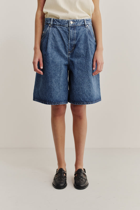 Women's shorts, wide-fit pleated denim, stone-washed indigo blue, made from organic and recycled cotton.