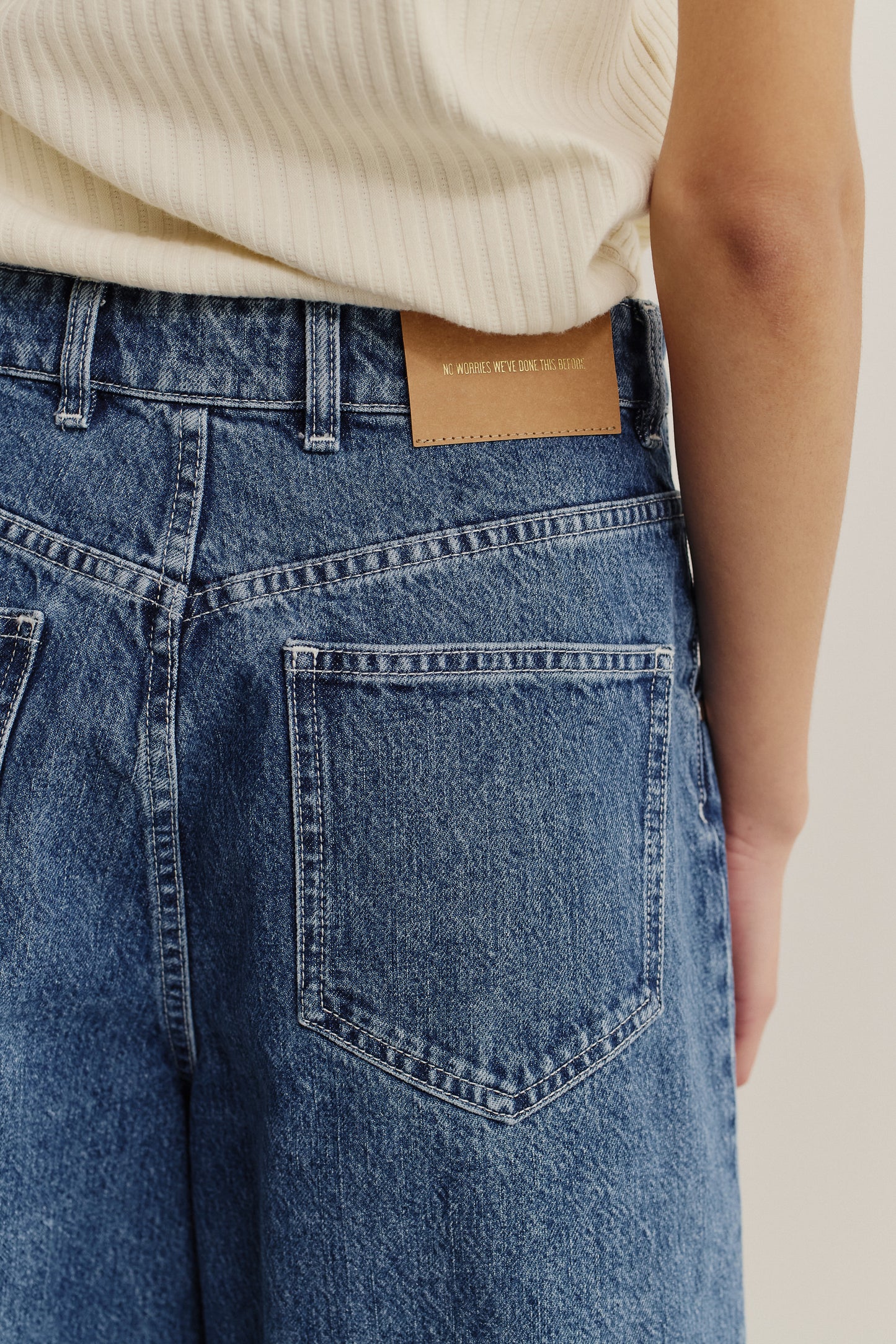 Women's shorts, cotton mix denim, stone washed blue, with a brown leather patch on the back waistband.