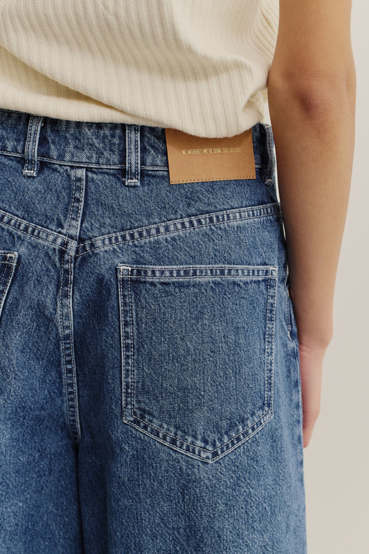 Women's shorts, cotton mix denim, stone washed blue, with a brown leather patch on the back waistband.
