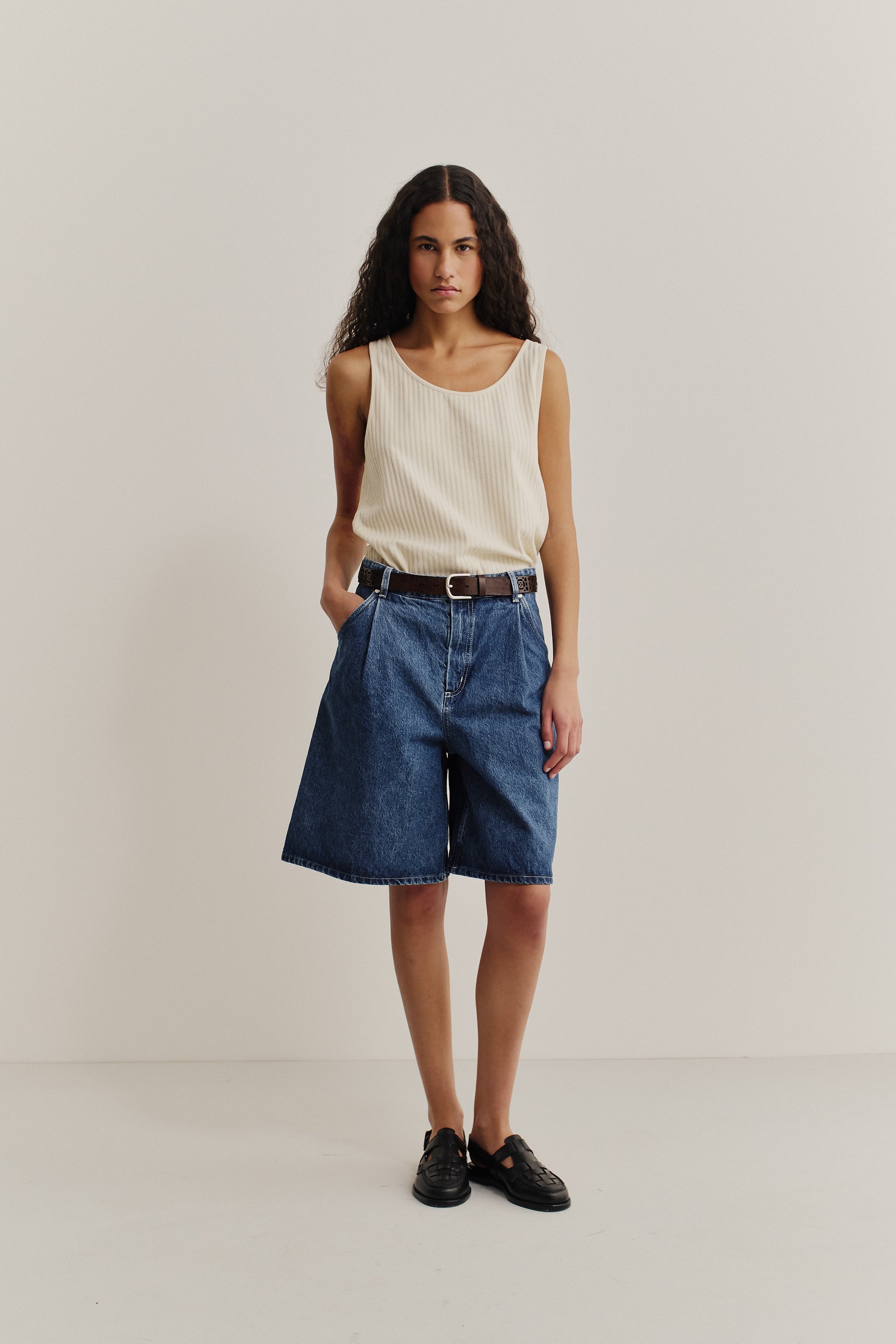Women's shorts, cotton mix denim, stone washed indigo, wide fit, pleated, with a brown belt.