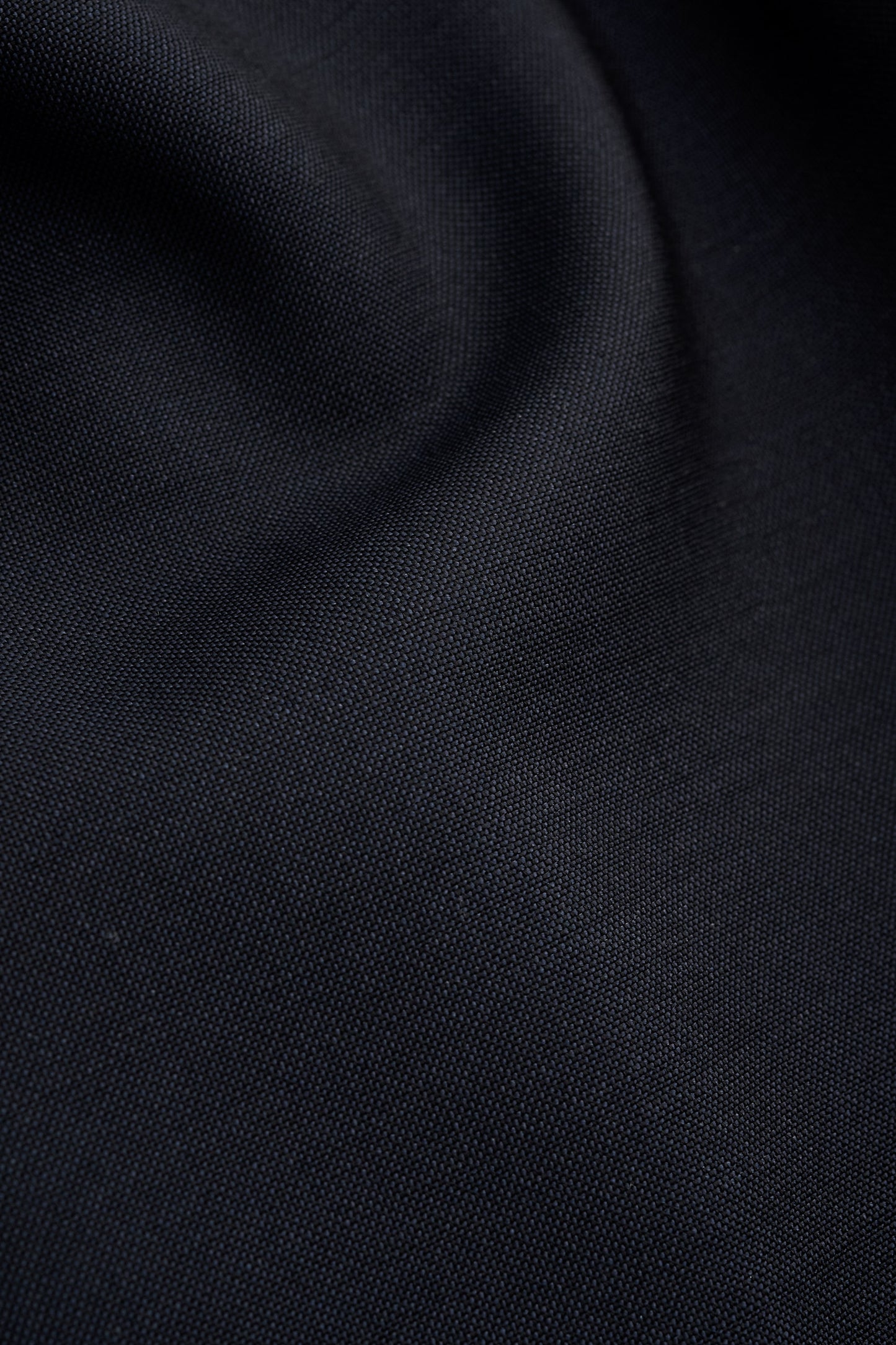 Men's long pants, virgin wool, dark navy, close-up of fabric texture.