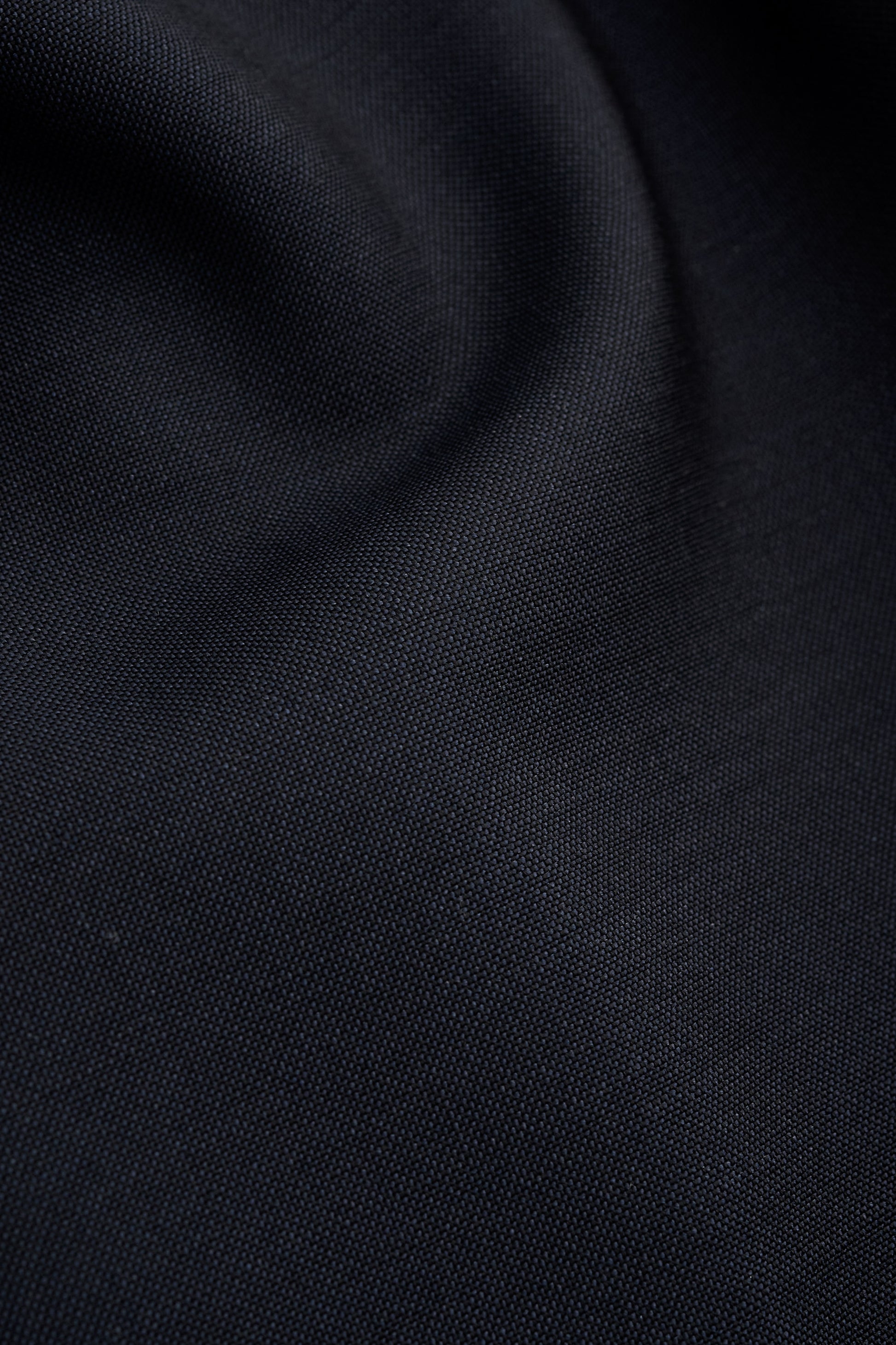 Men's long pants, virgin wool, dark navy, close-up of fabric texture.