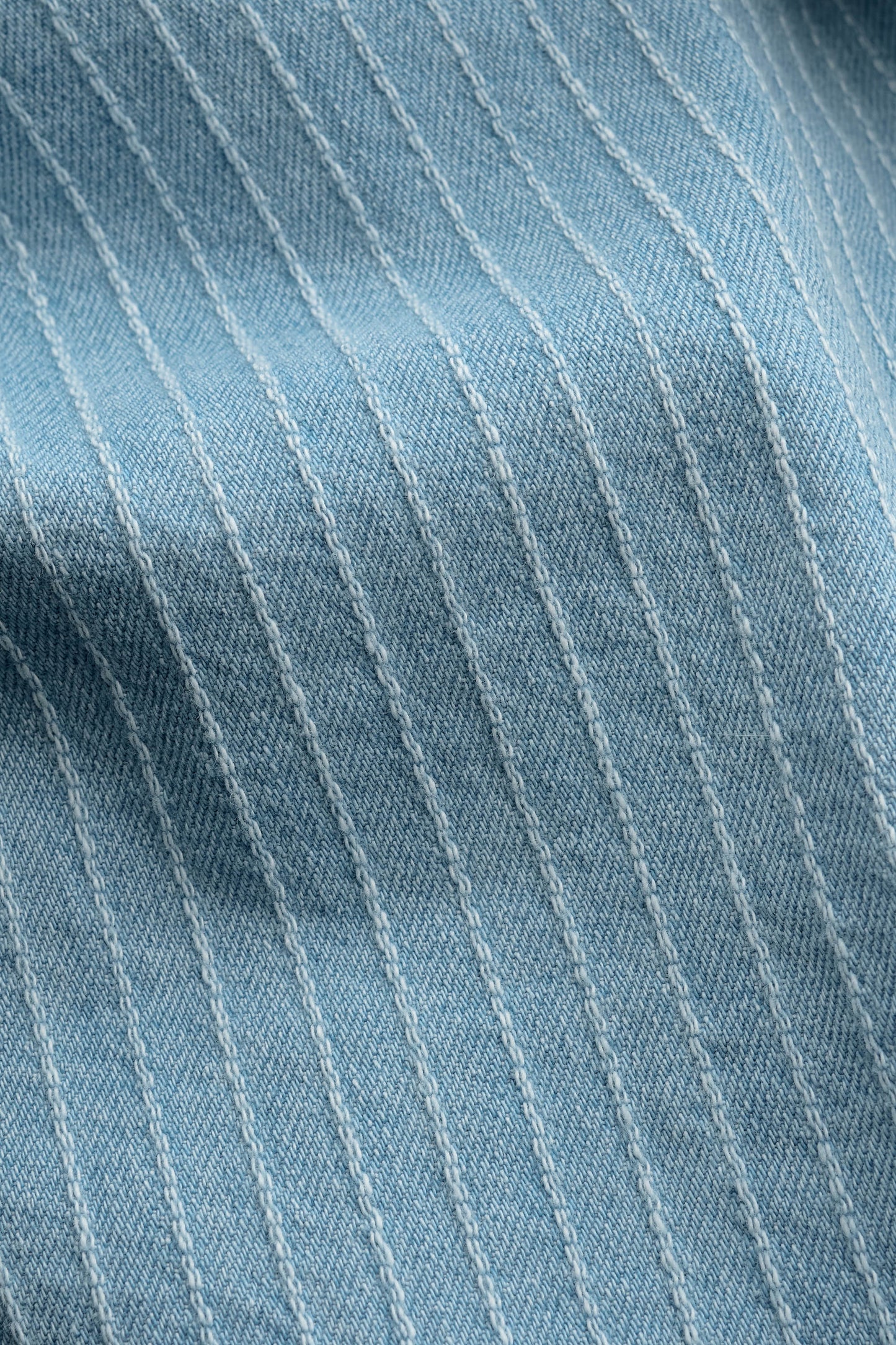 Men's pants, organic cotton light blue denim with subtle white pinstripes, washed finish.