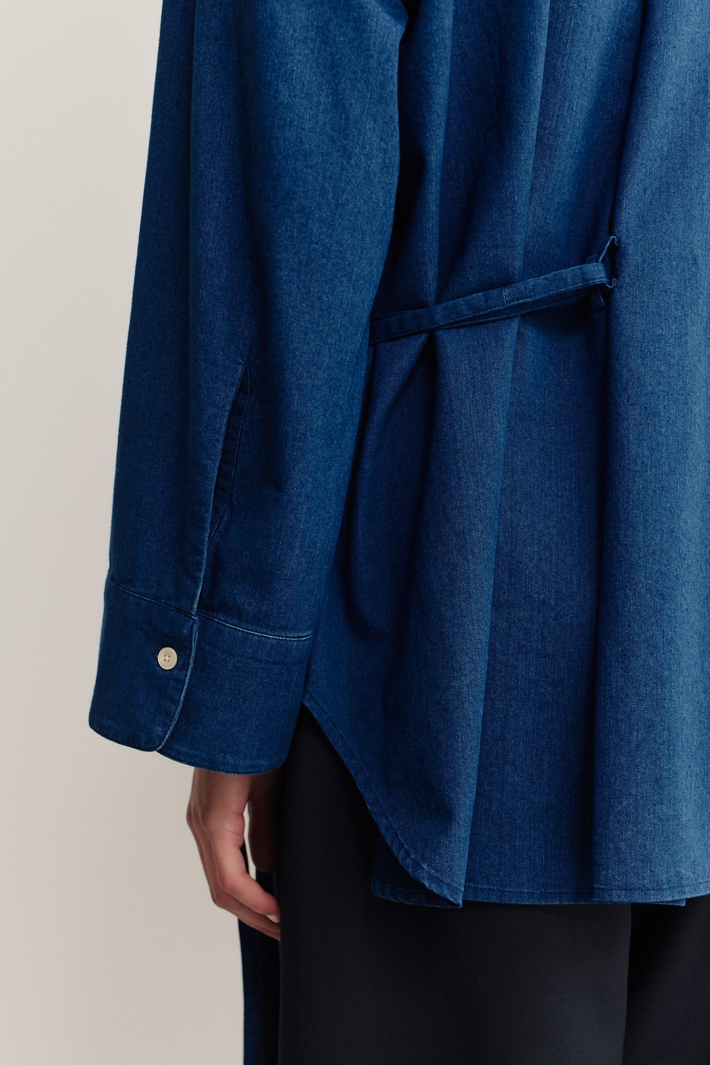 Women's long-sleeved shirt, washed indigo cotton, wide oversized fit, curved hem, and folded back detail.