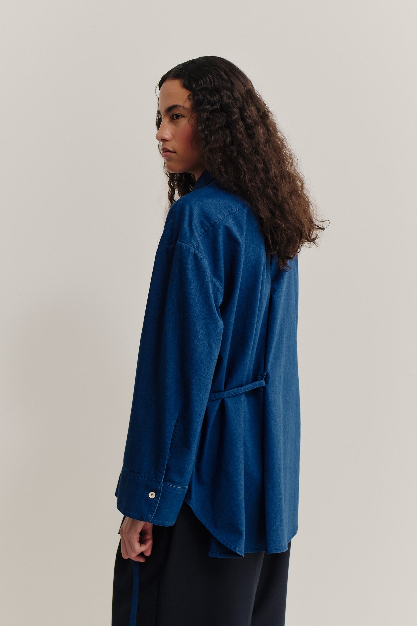 Women's long-sleeved shirt, washed indigo cotton, oversized fit, curved hem, and folded back detail.