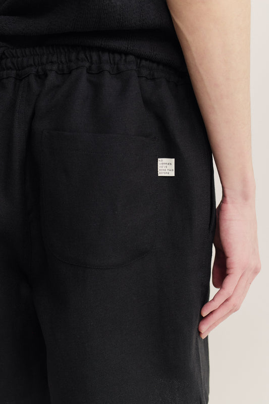 Men's shorts, black cotton blend, pre-washed with irregular wavy stripes, featuring a back patch pocket and label.